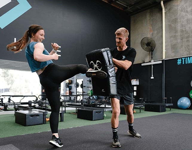 Woman and exercise trainer doing leg kicking workout